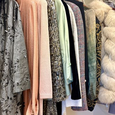 Assortment of vintage and contemporary women's outerwear and tops, featuring a metallic floral cutout coat, a faux fur vest, and...