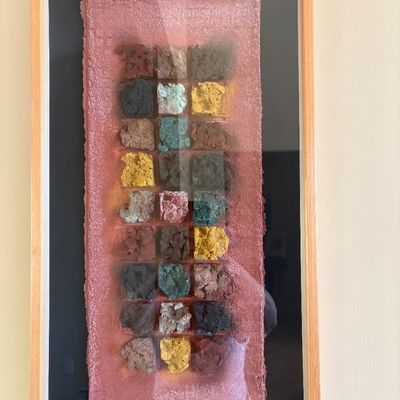 Framed contemporary mixed-media textile art piece featuring a grid of colorful, textured fiber squares on a pink handmade paper background.