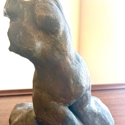 Abstract bronze sculpture of a female torso, featuring a textured, weathered patina and a modern, organic form.
