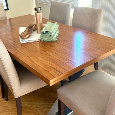 Modern dining set featuring a rectangular wood-grain table with a metal base, paired with six upholstered high-back chairs in a neutral...