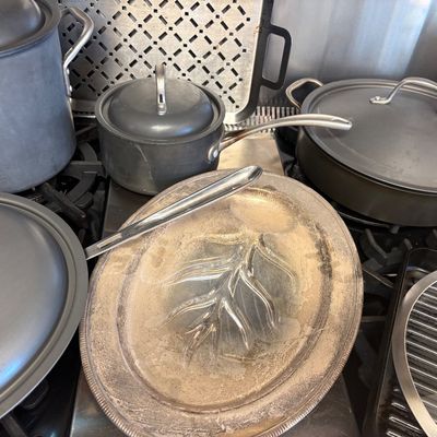 Assorted Calphalon hard-anodized nonstick cookware, including pots, pans, and lids, shown alongside a vintage silver-plated tree-and-well...
