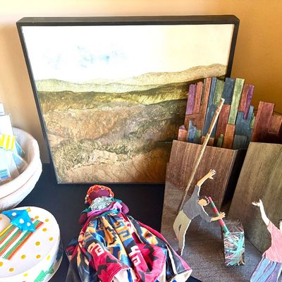 Assorted decorative items including a framed landscape painting, a colorful fabric doll, a small decorated round box, and whimsical...
