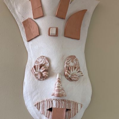 Handcrafted ceramic wall mask featuring a white textured base with terracotta clay accents forming abstract facial features and a...