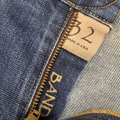 Close-up of Band of Outsiders blue jeans, size 32, featuring a brass YKK zipper fly and a "Made in USA" tag.