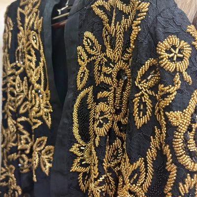 Vintage black lace jacket featuring intricate gold and black beadwork in a floral motif, circa 1980s.