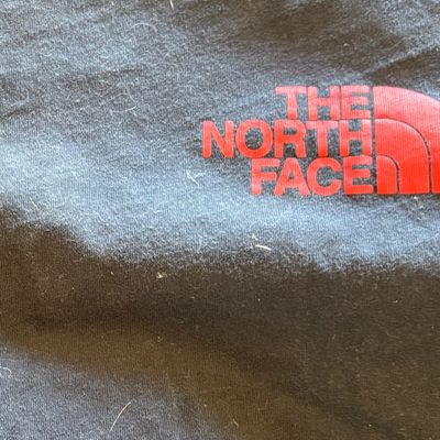 Close-up of a black The North Face garment featuring a red printed logo.