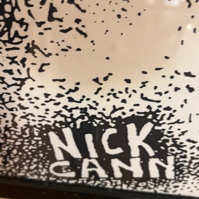 Close-up detail of a framed black and white graphic print showing the artist's signature "Nick Cann" in the bottom corner.