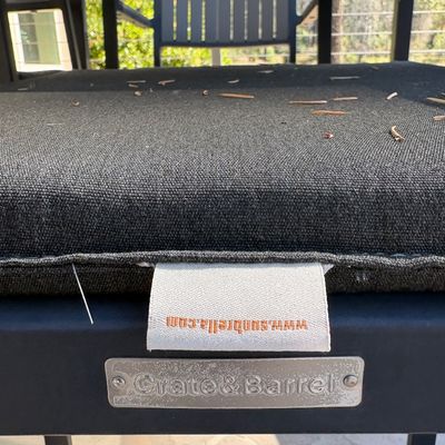 Crate & Barrel outdoor furniture piece featuring a dark grey Sunbrella cushion, showing the brand labels.