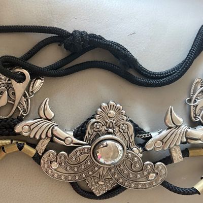 Vintage Southwestern-style black cord belt featuring ornate silver-tone metal slides, charms, and brass-tone accents.