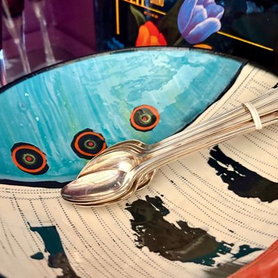 Artistic ceramic bowl featuring a hand-painted abstract design in turquoise, black, and white, holding a bundle of vintage silver-plated...