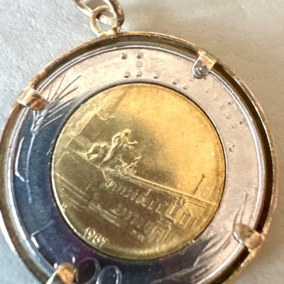 Italian 500 lire bimetallic coin dated 1987, mounted in a gold-tone bezel pendant frame.
