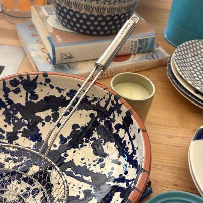 Assorted kitchenware including a large blue and white splatter-paint ceramic bowl with a wire strainer, a Polish pottery lidded casserole...