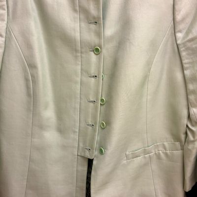 Light green women's blazer featuring a high collar, button-up front closure, and a single welt pocket.