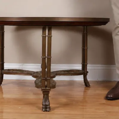 Vintage Neoclassical style round side table featuring a brass-finished metal base with faux-bamboo legs, claw feet, and a dark wood top.
