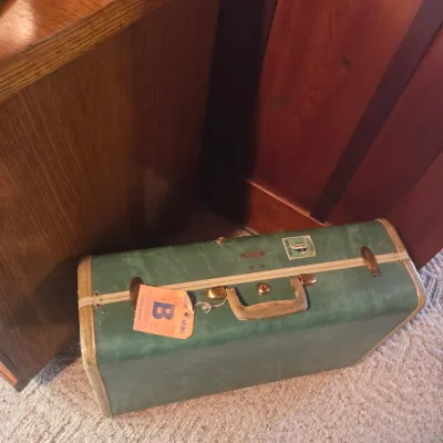 Sale Photo Thumbnail #80: Vintage green hard-shell suitcase with brass hardware, a tan handle, and an attached Eastern Airlines luggage tag.