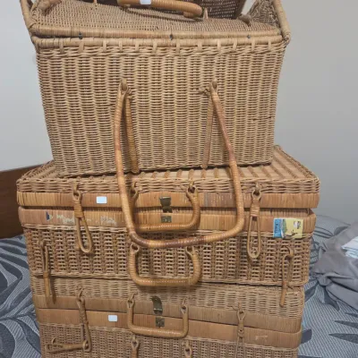 Sale Photo Thumbnail #2: Stack of vintage woven wicker picnic baskets and suitcases, featuring sturdy handles and metal latches, showing some wear consistent with age.