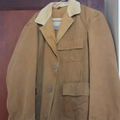 Sale Photo Thumbnail #68: Vintage Montana canvas hunting jacket in tan with a corduroy collar, featuring multiple utility pockets and button closures.