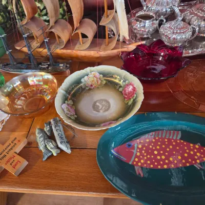 Sale Photo Thumbnail #88: Assorted vintage tabletop decor, including a hand-painted fish platter, floral porcelain bowls, iridescent carnival glass, and a silver-plated tea service.