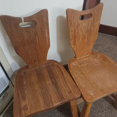 Sale Photo Thumbnail #67: Pair of rustic wooden dining chairs with carved backs featuring integrated handle cutouts, showing some wear to the finish.