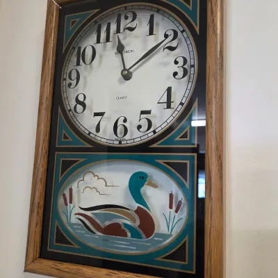 Sale Photo Thumbnail #58: Vintage Verichron quartz wall clock featuring a wooden frame and a decorative glass panel with a mallard duck illustration, circa 1980s.