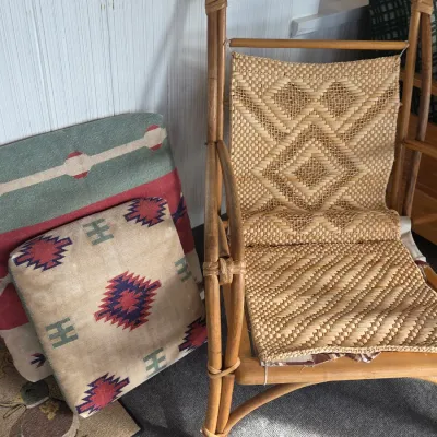Sale Photo Thumbnail #19: Vintage bamboo or rattan armchair with a woven wicker seat and back, shown alongside Southwestern-style patterned throw pillows.