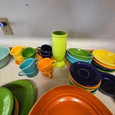 Sale Photo Thumbnail #29: Assorted vintage and contemporary Fiesta dinnerware, including colorful mugs, plates, bowls, and a lime green vase.