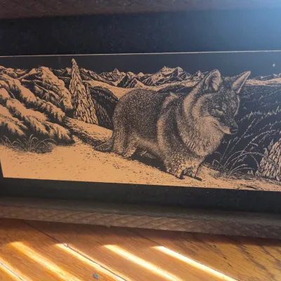 Sale Photo Thumbnail #99: Framed scratchboard art depicting a wolf in a snowy mountain landscape, set in a rustic wooden frame.