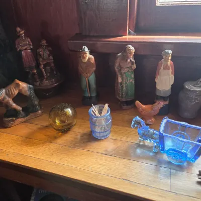 Sale Photo Thumbnail #93: Collection of vintage figurines and glass novelties, including hand-painted wooden folk art figures, a blue glass horse and cart, and a carved wooden horse.
