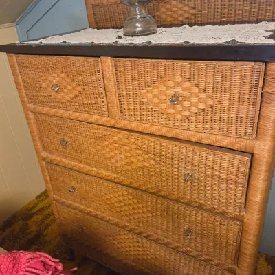 Sale Photo Thumbnail #44: Vintage wicker and rattan five-drawer chest of drawers featuring a woven diamond pattern, glass knobs, and a dark wood top, topped with a vintage glass oil lamp.