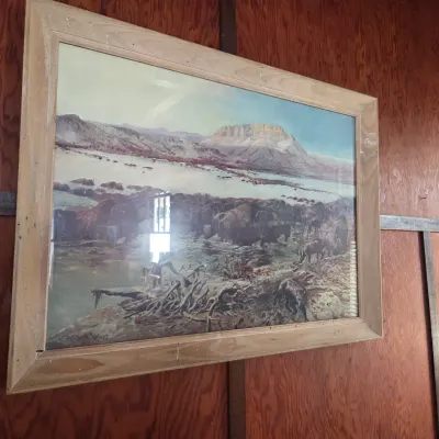 Sale Photo Thumbnail #98: Framed print of a Western landscape featuring a herd of bison near a river, housed in a rustic light wood frame.
