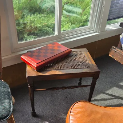 Sale Photo Thumbnail #21: Vintage wooden side table with a cane-inlay top, featuring turned legs and a lower stretcher, shown with a wooden checkerboard box on top.