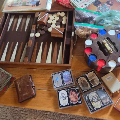 Sale Photo Thumbnail #91: Collection of vintage games and accessories, including a folding backgammon set, a wooden poker chip carousel, chess pieces, and several decks of themed playing cards.