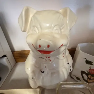 Sale Photo Thumbnail #28: Vintage Shawnee Pottery "Smiley" pig cookie jar, featuring hand-painted red and black details on a cream glaze.
