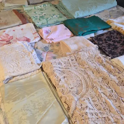 Sale Photo Thumbnail #39: Assortment of vintage linens, tablecloths, and lace textiles displayed on a bed.