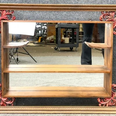 Sale Photo Thumbnail #11: Vintage wooden shadow box mirror featuring a carved frame with red-accented corner flourishes and built-in display shelves.