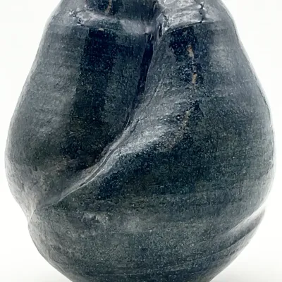 Sale Photo Thumbnail #2: Studio art pottery vase with an organic, biomorphic shape and a textured dark blue-grey glaze.
