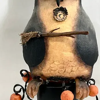 Sale Photo Thumbnail #55: Primitive-style Halloween owl figurine wearing a tall witch hat, holding a broom, and perched on a yellow and black celestial-themed pedestal.