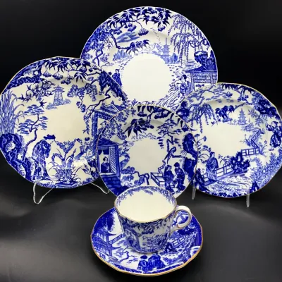 Sale Photo Thumbnail #73: Vintage Booths "Real Old Willow" blue and white transferware china set, including plates of various sizes and a matching teacup and saucer with gold-trimmed rims.