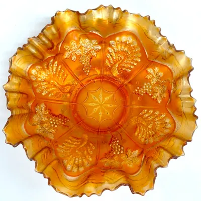 Sale Photo Thumbnail #62: Vintage marigold carnival glass bowl featuring a ruffled edge and embossed peacock and grape motifs.