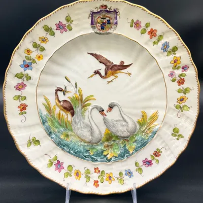 Sale Photo Thumbnail #64: Meissen Swan Service porcelain plate, featuring a relief design of swans and herons, a floral border, and a coat of arms at the top.