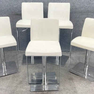 Sale Photo Thumbnail #84: Set of five modern bar stools featuring white leather upholstery, chrome pedestal bases, and integrated footrests.