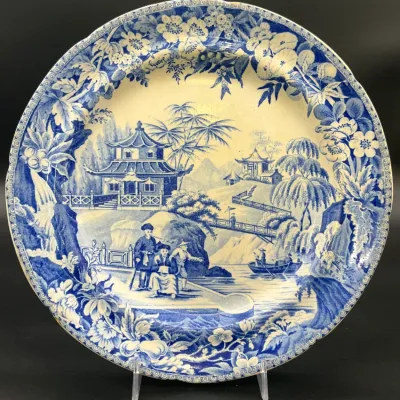 Sale Photo Thumbnail #60: Antique blue and white transferware plate featuring a detailed chinoiserie landscape with figures, pagodas, and a floral border.