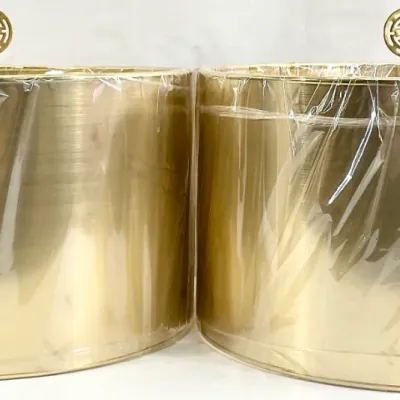 Sale Photo Thumbnail #94: Pair of vintage mid-century modern gold foil drum lamp shades, preserved in original protective plastic wrap and topped with decorative brass finials.