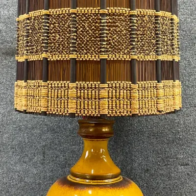 Sale Photo Thumbnail #91: Mid-century modern ceramic table lamp featuring a mustard yellow and brown glazed base, topped with a tall woven rattan and grasscloth drum shade.