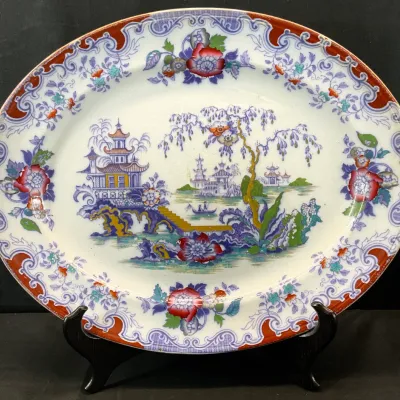 Sale Photo Thumbnail #14: Antique ironstone transferware platter in a Chinoiserie pattern, featuring a central pagoda landscape with a floral border in red, blue, and green tones.