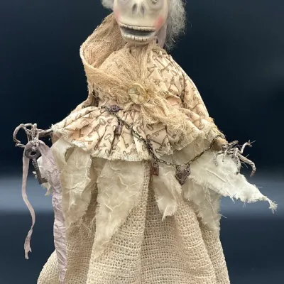 Sale Photo Thumbnail #82: Handcrafted gothic art doll featuring a skeletal face, top hat, and layered fabric dress adorned with keys and chains.