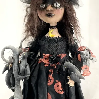 Sale Photo Thumbnail #75: Handcrafted folk art witch doll featuring a black and orange pumpkin-patterned dress, tulle accents, and fabric crows perched on her shoulder and staff.