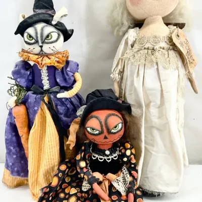 Sale Photo Thumbnail #52: Three whimsical, folk-art style Halloween and holiday fabric dolls, including a witch cat, a pumpkin-headed figure, and a white-gowned angel with a halo.