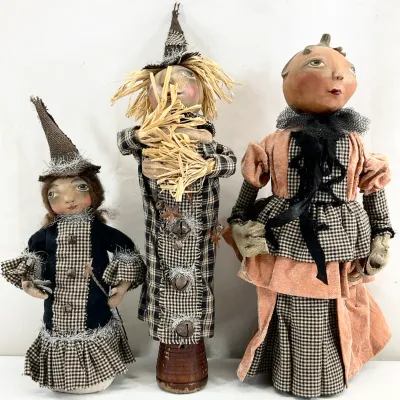 Sale Photo Thumbnail #72: Trio of folk art Halloween dolls featuring a witch, a scarecrow, and a pumpkin figure, crafted with plaid fabric, tinsel, and rustic details.