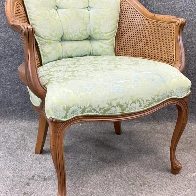 Sale Photo Thumbnail #30: Vintage French Provincial style barrel-back armchair featuring a cane back, cabriole legs, and light green floral damask upholstery.